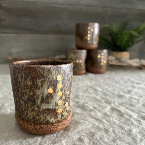 Handmade stoneware pottery. Dark speckled squish cup with gold luster dot accents.