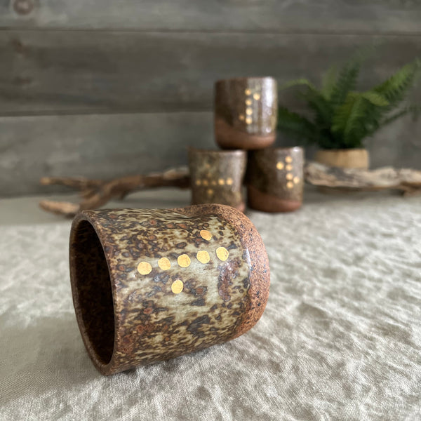 Handmade stoneware pottery. Dark speckled squish cup with gold luster dot accents.