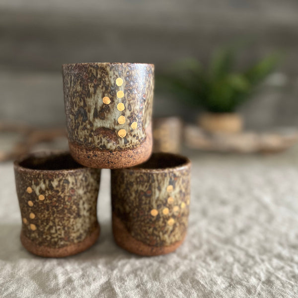 Handmade stoneware pottery. Dark speckled squish cup with gold luster dot accents.