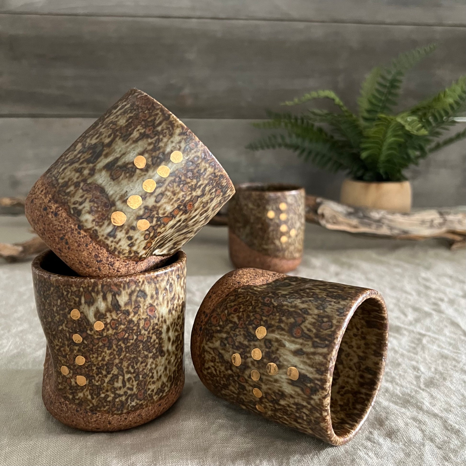 Handmade stoneware pottery. Dark speckled squish cup with gold luster dot accents.