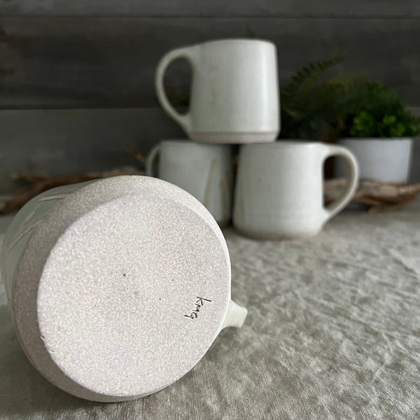 Handmade stoneware pottery. White coffee mug with lines and dot accents.